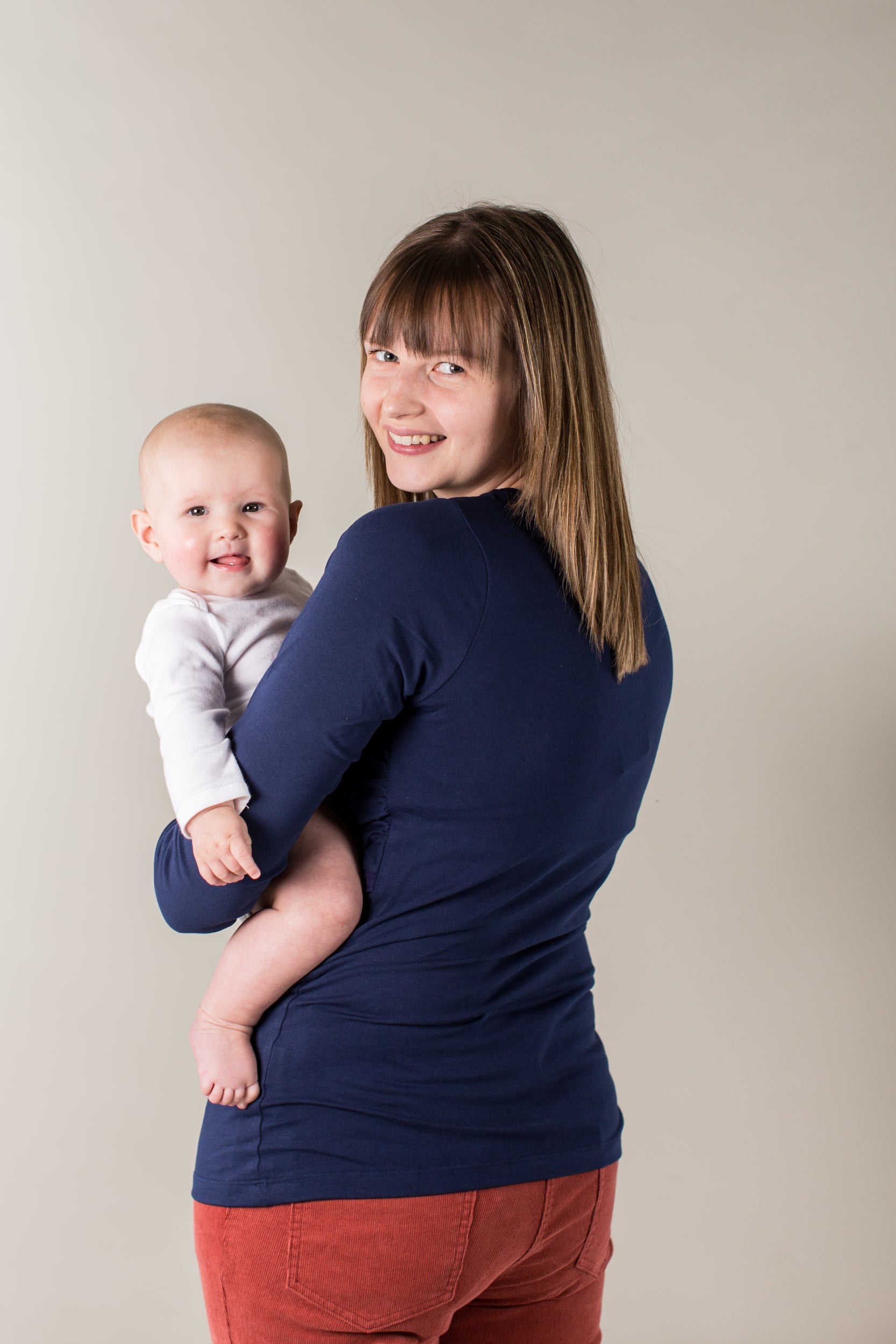 Woman holding a baby against a plain background