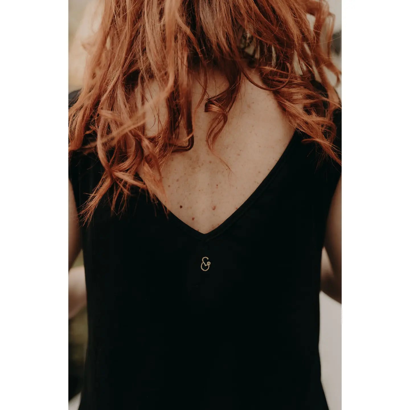 Person wearing a black sleeveless top with a small logo on a blurred background