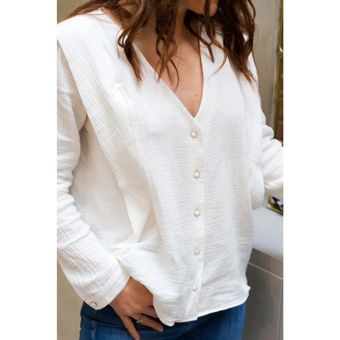 White button-up blouse worn by a person with a blurred background