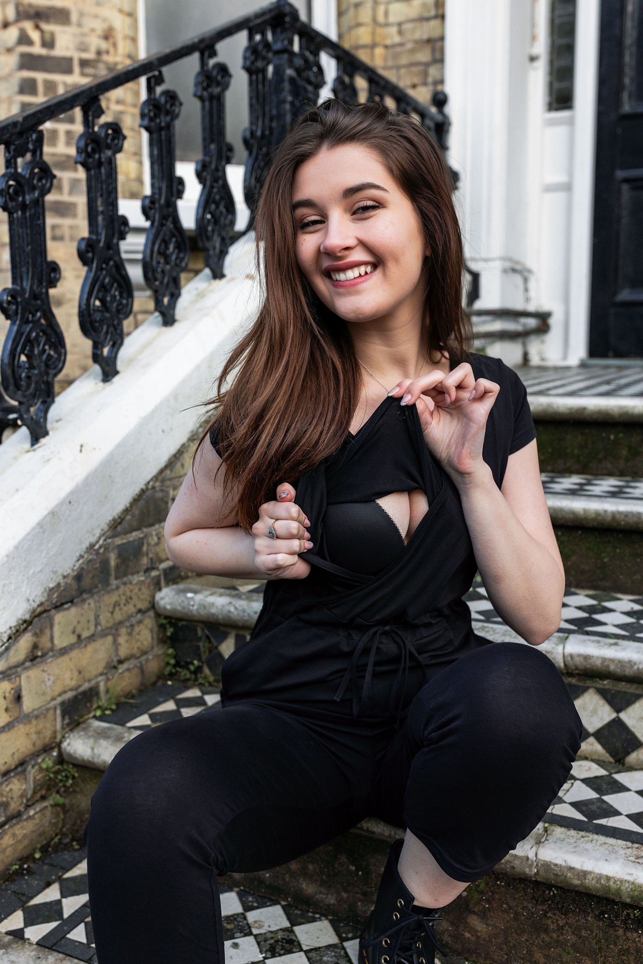 Woman in a black jumpsuit showing the boob access sitting outdoors.