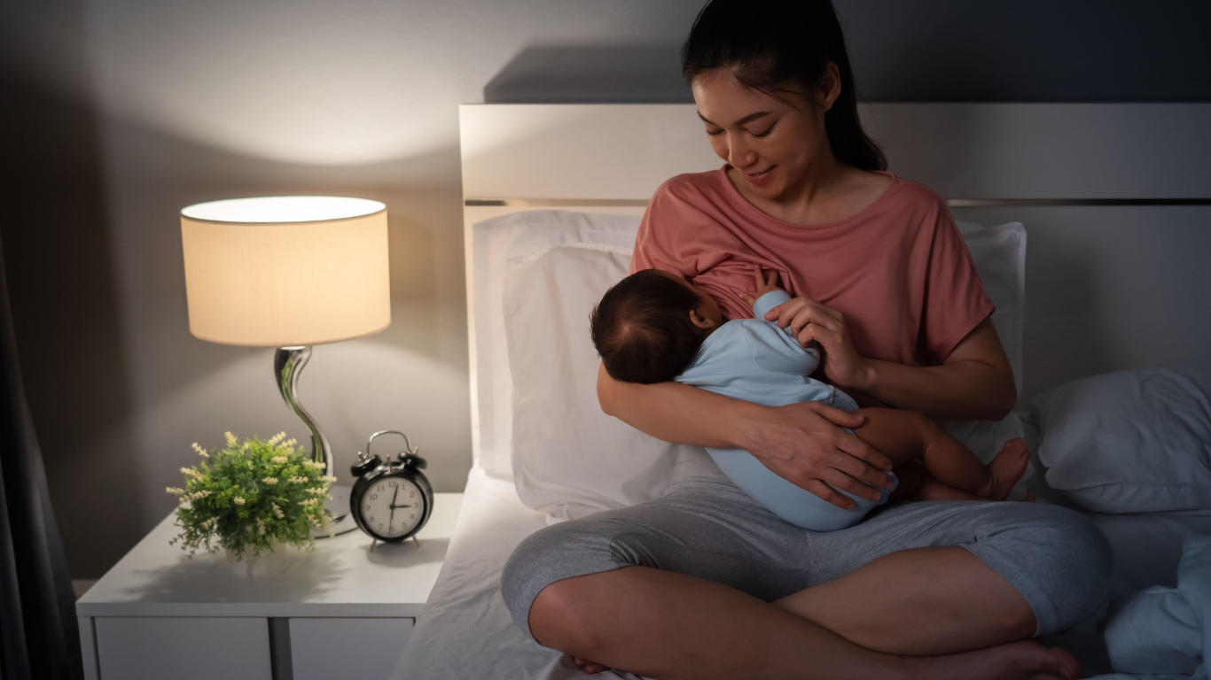 Mum breastfeeding in bed with a soft light