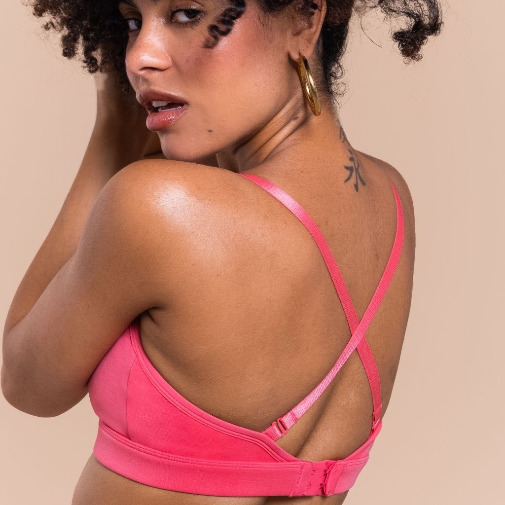 Woman wearing a neon pink nursing bra with crossed straps