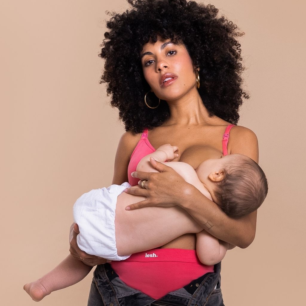 Woman breastfeeding a baby wearing a neon pink nursing bra