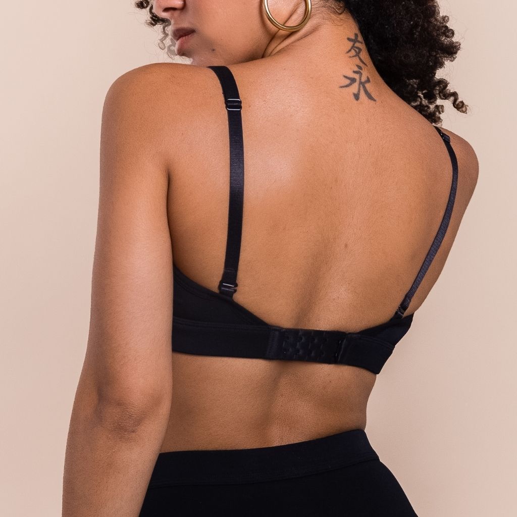 Person wearing a black bralette on a beige background