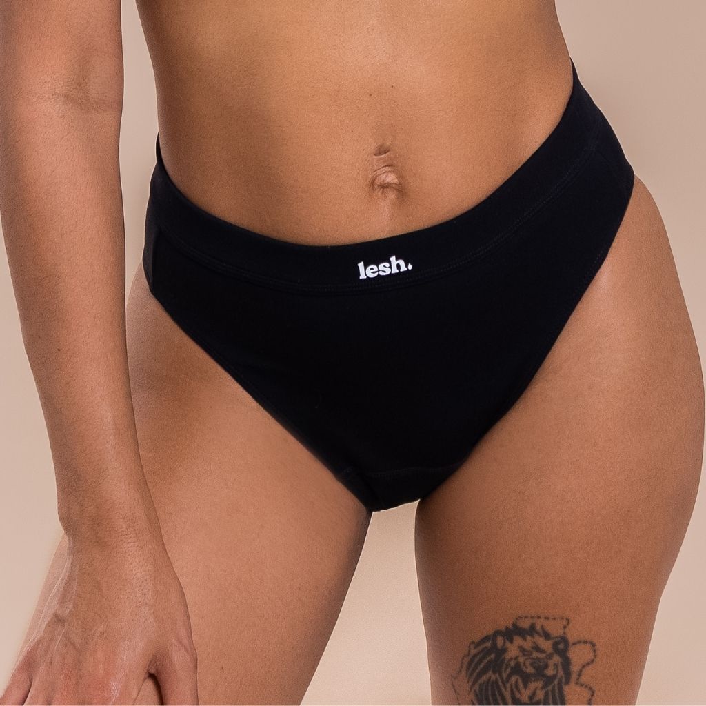 Person wearing black underwear with 'lesh' branding on a beige background