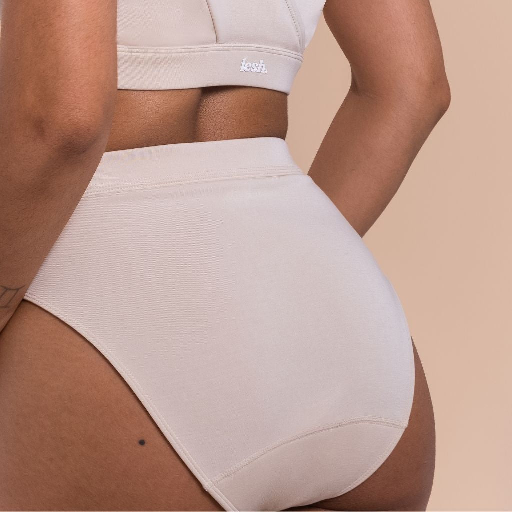 Beige high-waisted underwear worn by a person on a beige background