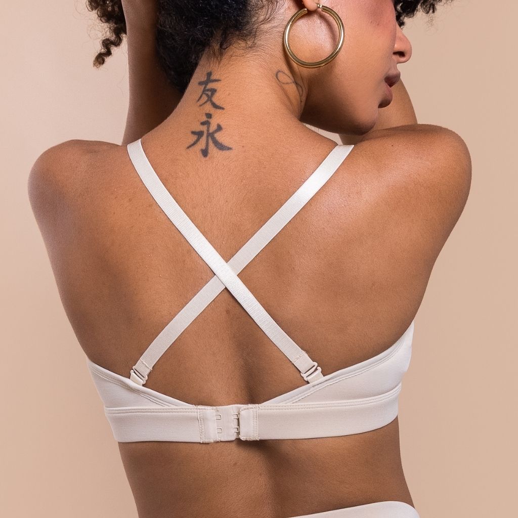 woman showing her back wearing a white bra with crossed straps