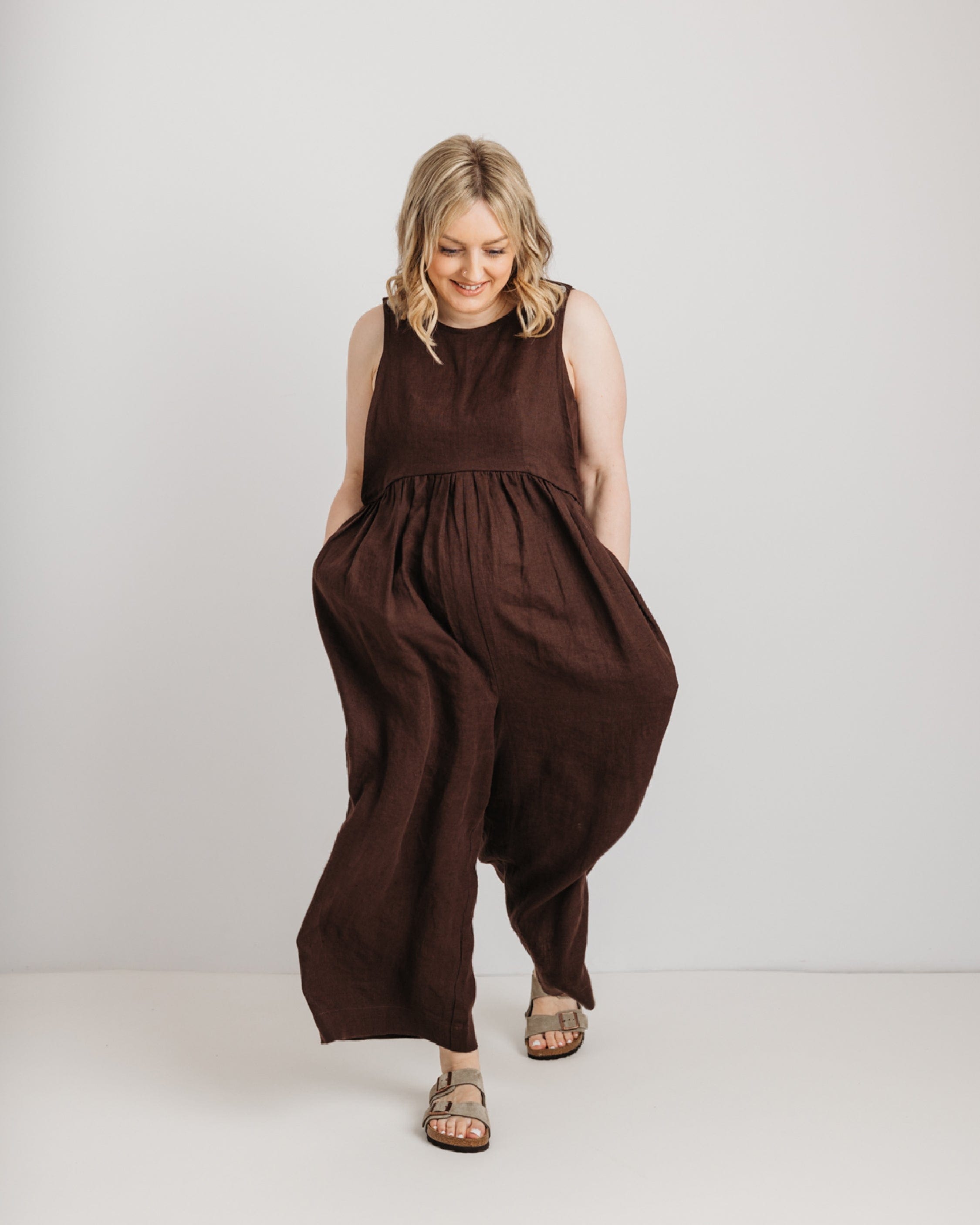 Woman wearing a brown sleeveless jumpsuit on a white background