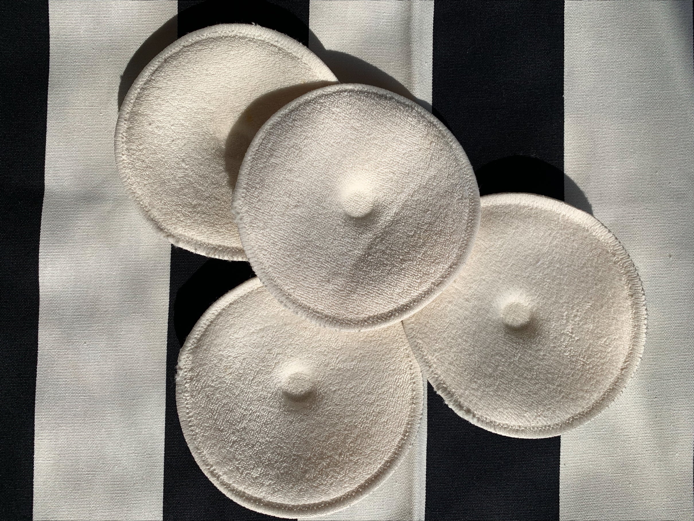 Four white soft pads on a black and white striped background