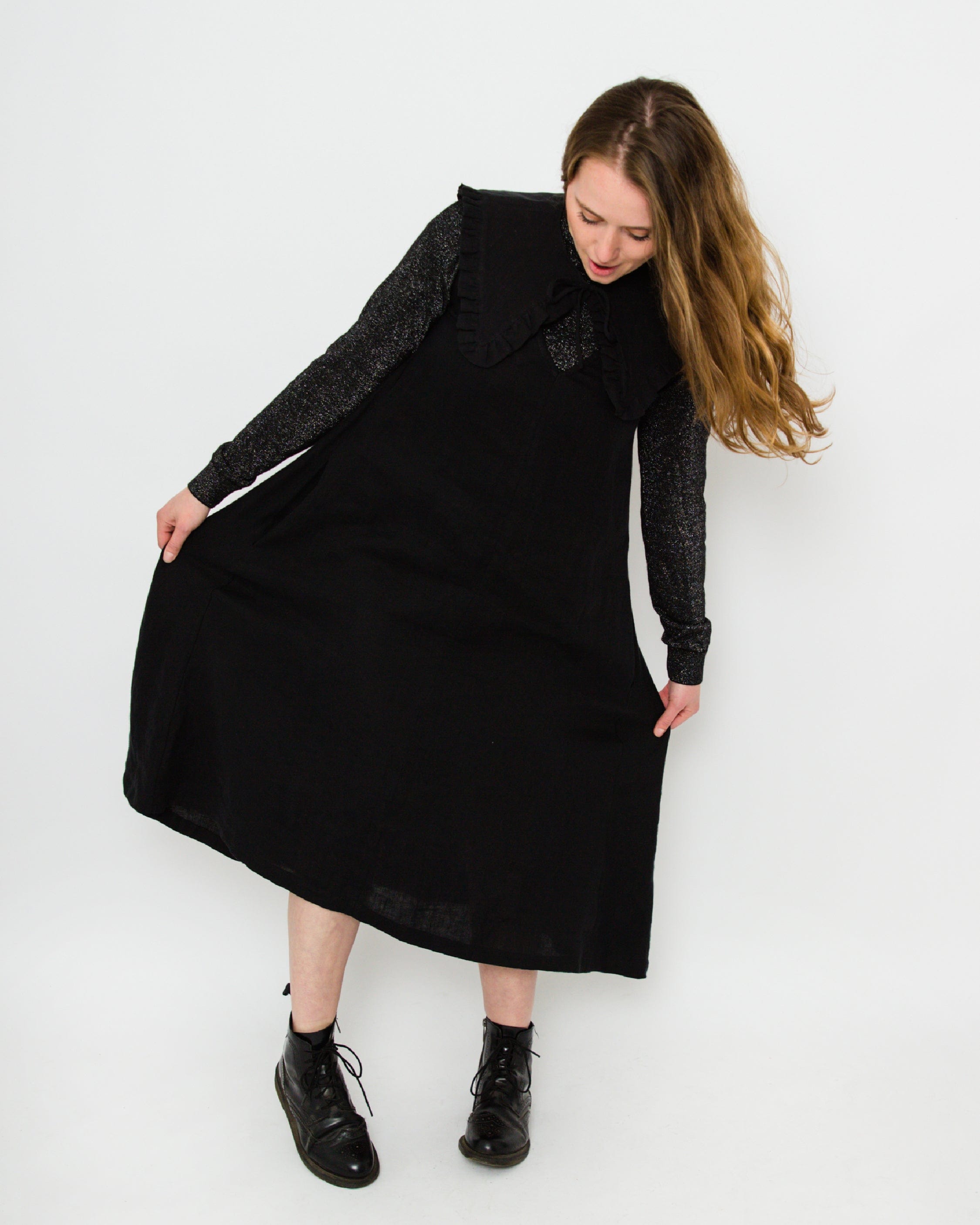 Woman wearing a black dress with a textured sleeve against a white background