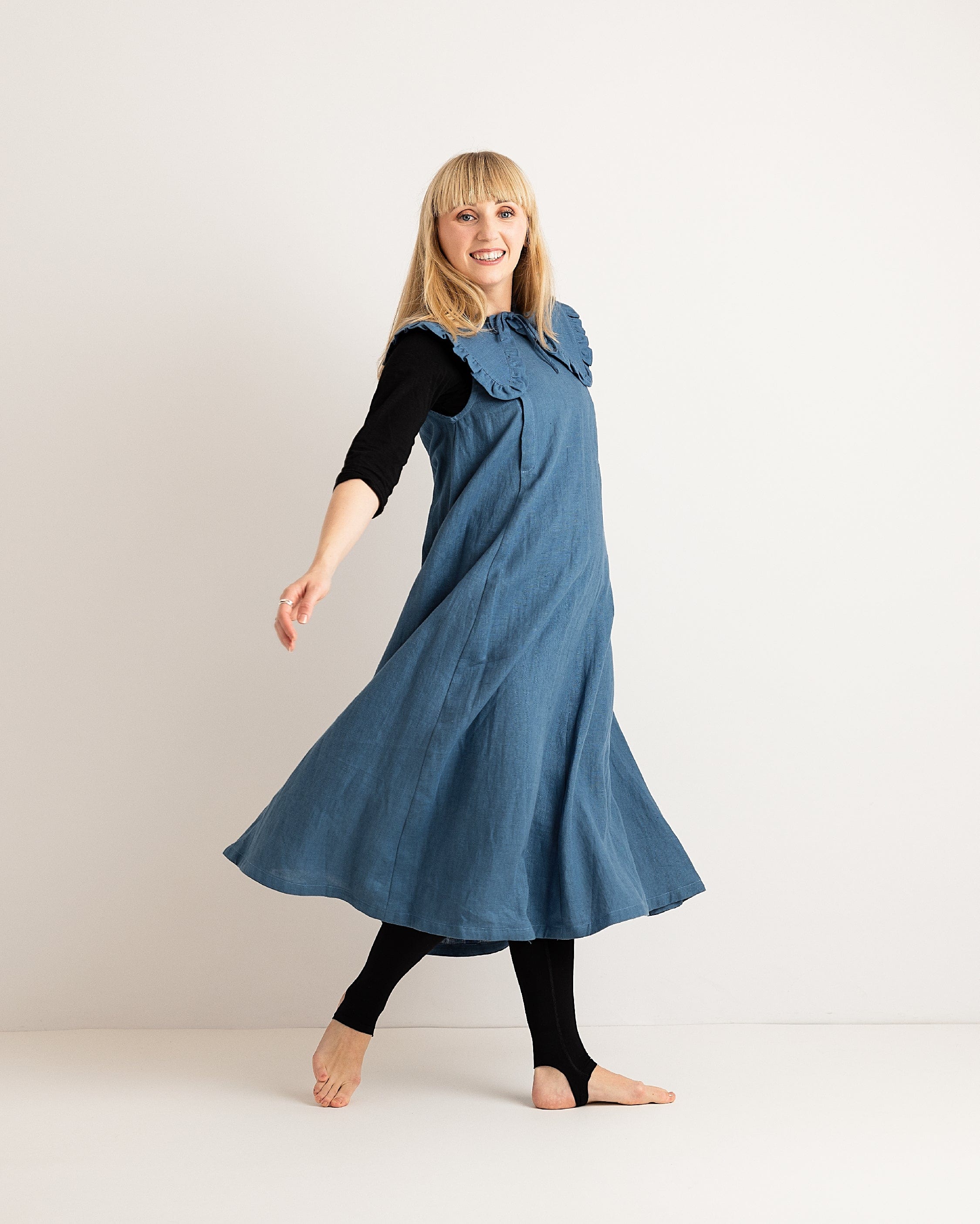 Woman wearing a blue dress with a black top and leggings on a white background