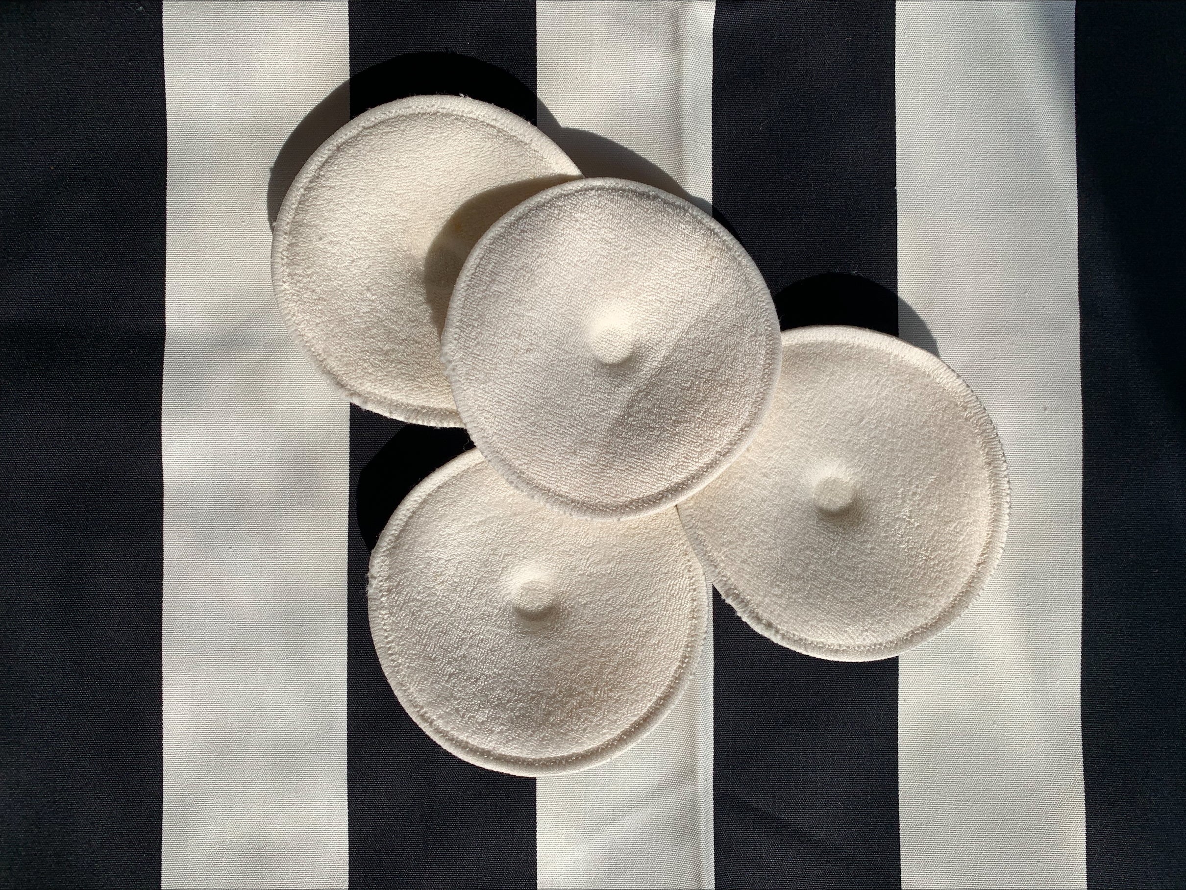 Four white soft pads on a black and white striped background