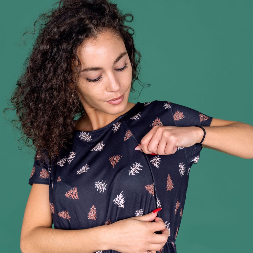 Woman adjusting a navy blue dress with floral patterns against a green background