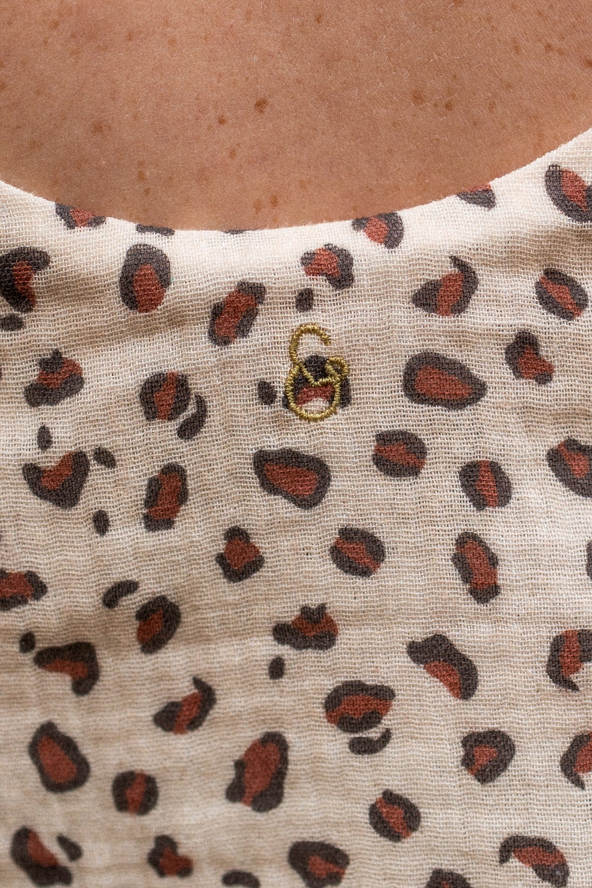 Close-up of a fabric with a leopard print pattern and a brand logo.