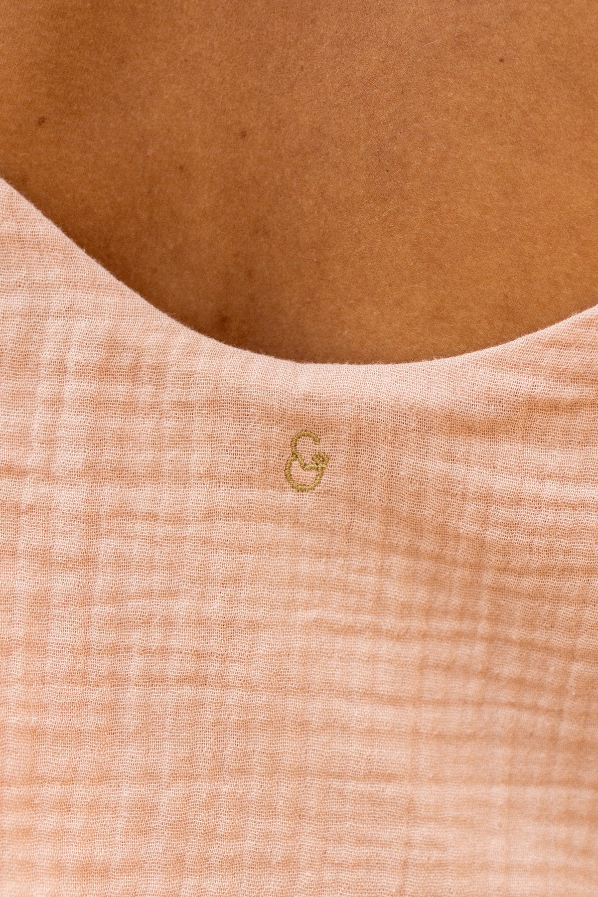 Close-up of a textured nude fabric with a small logo 