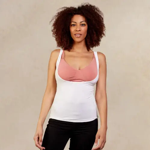 Woman wearing a white underbust top over a pink bralette against a beige background