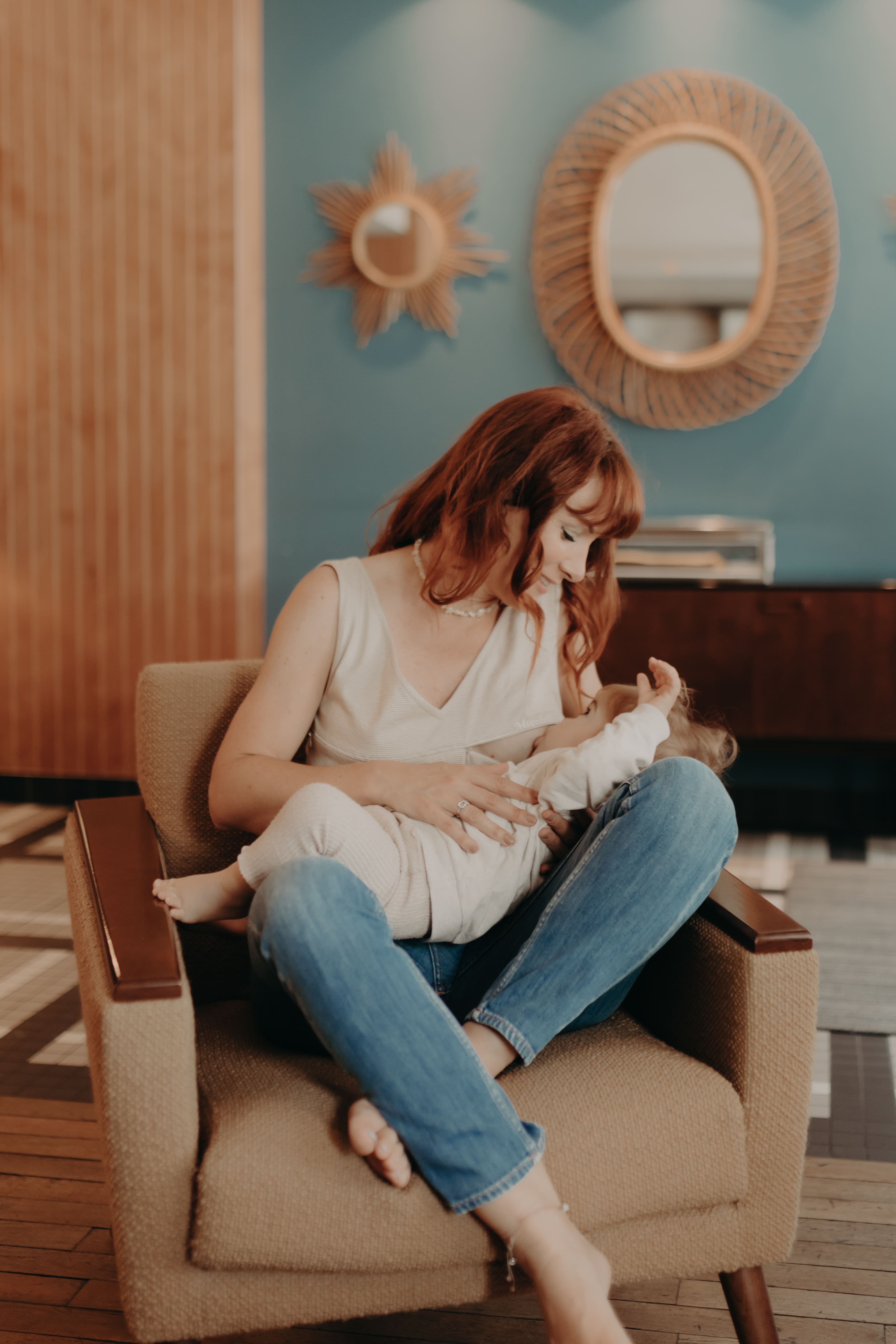 Woman breastfeeding  a baby in a room with decorative mirrors on the wall.